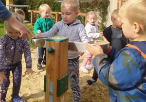 chłopcy sypią piasek do wagi na terenie ogródka "Słoneczna Akademia"